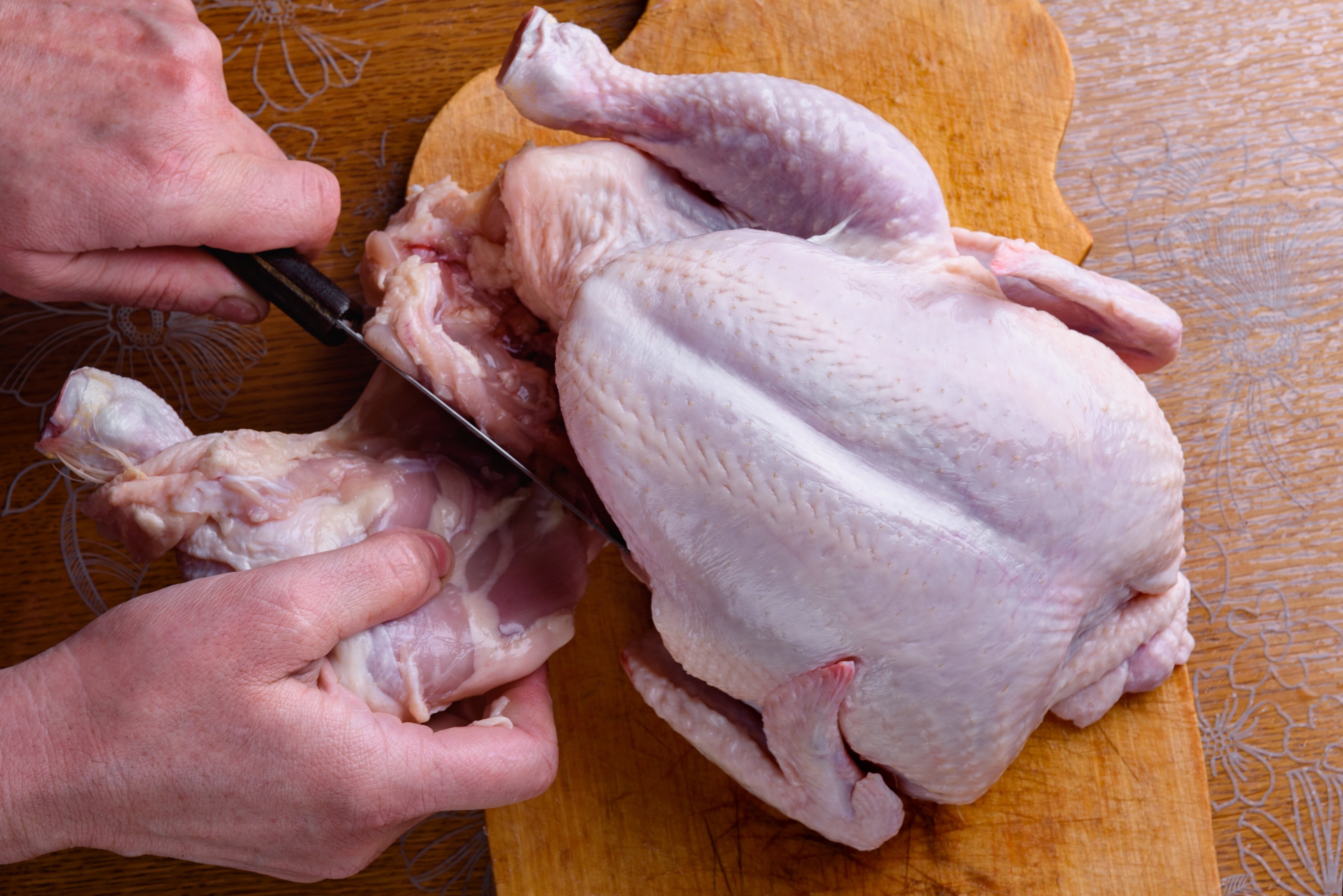 Hands cutting up a whole chicken