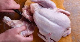 Hands cutting up a whole chicken